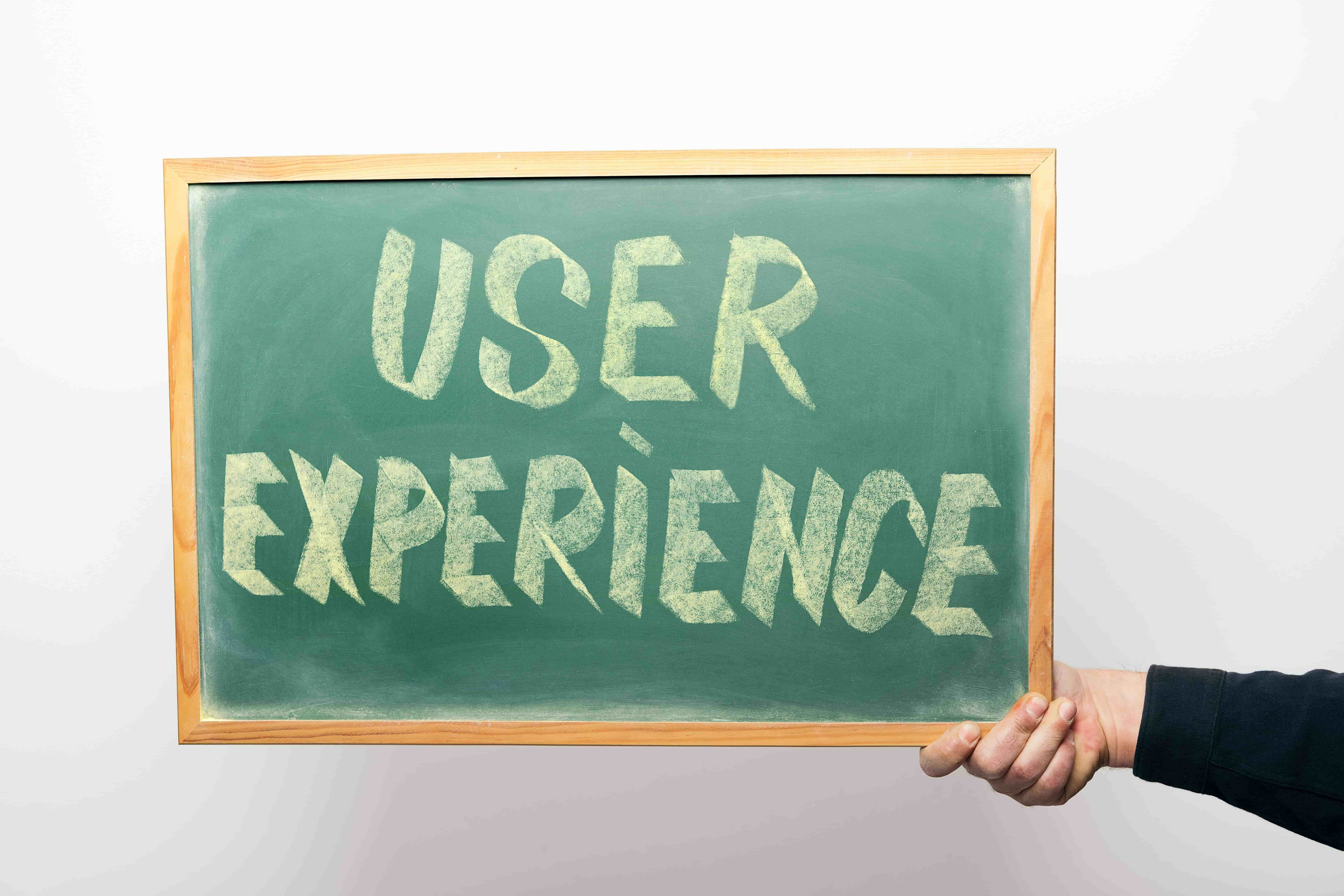 Napis User Experience na tabli - customer experience blog. 